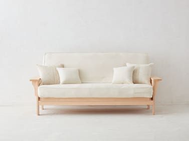 a white couch with four pillows on it and a wooden frame around the armrests