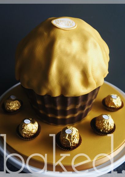 there is a yellow cake with chocolates on the plate and gold foil around it