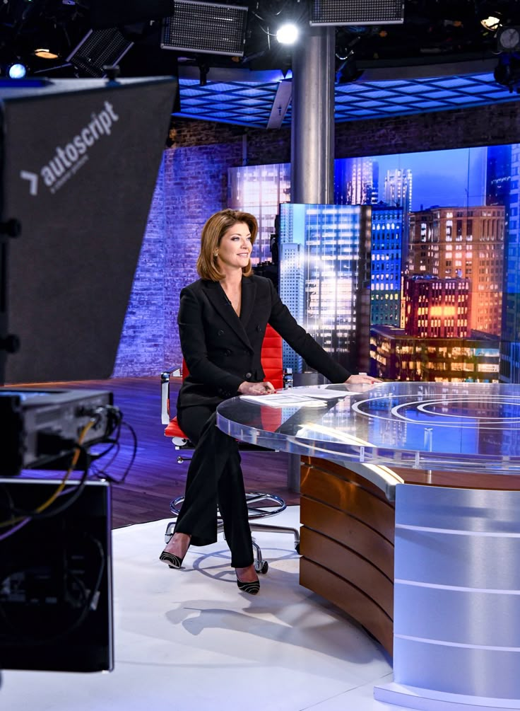 a woman sitting at a desk in front of a tv set