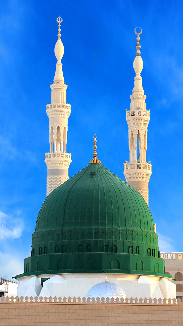 a large green dome on top of a white building with two minalis in the background