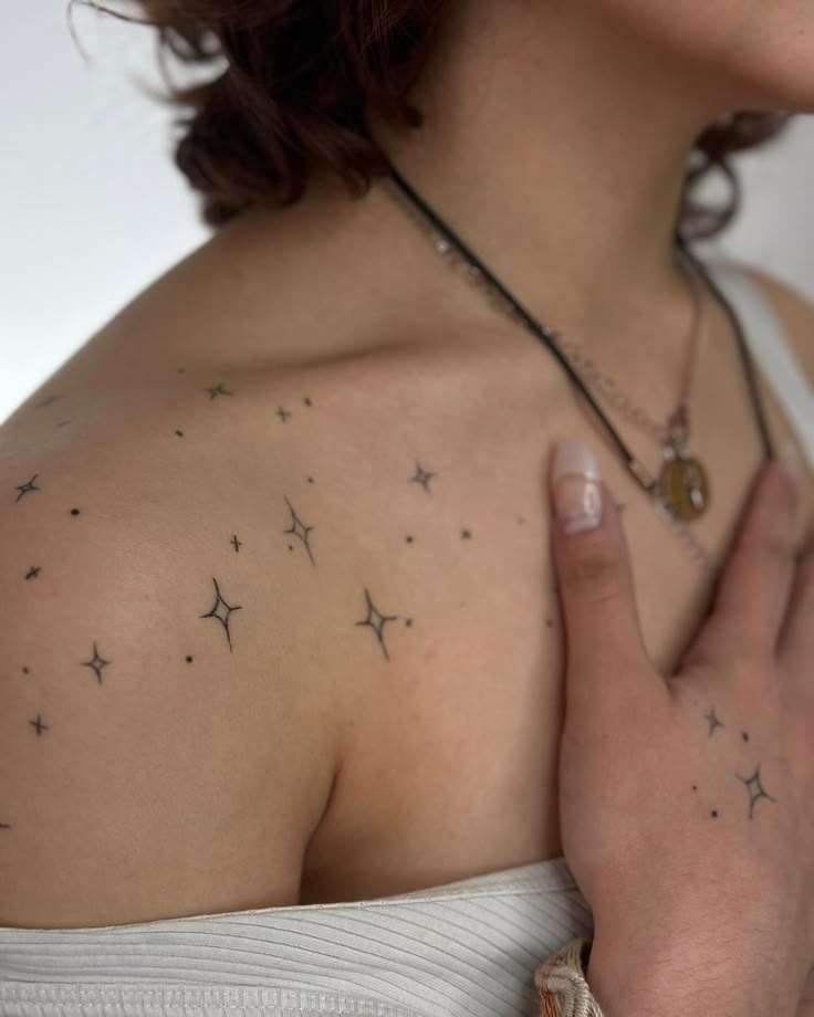 a woman with her hand on her chest and stars tattooed on her shoulder, looking at the camera