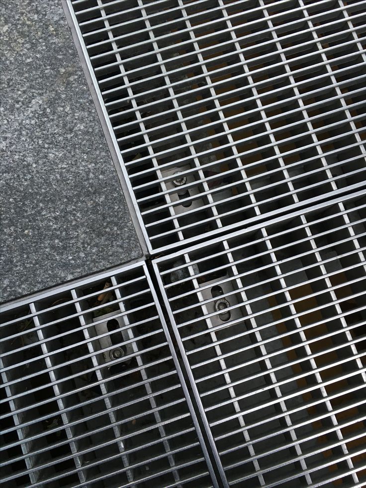 three metal grates sitting on top of a cement floor next to each other with holes in them