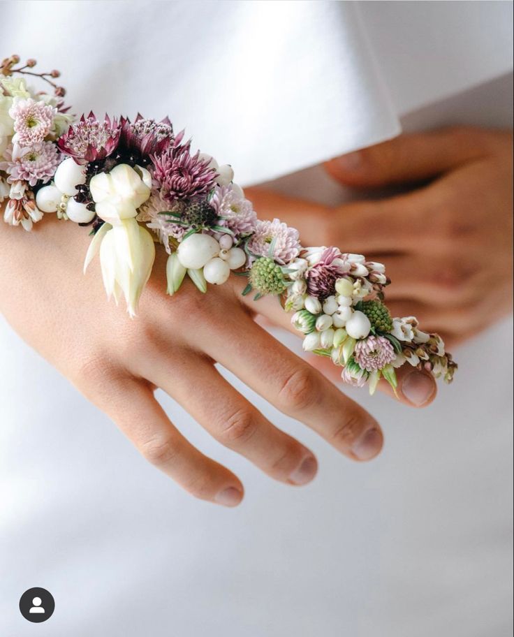 a close up of a person's hand wearing a bracelet with flowers on it