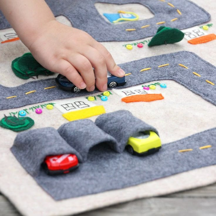 a child playing with cars and trucks on a play mat in the shape of a road