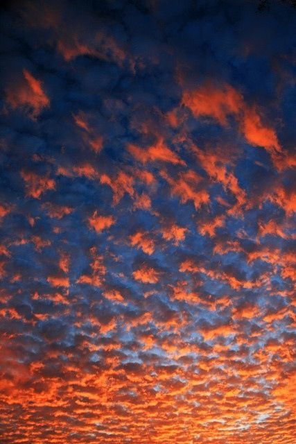 an orange and blue sky with clouds at sunset