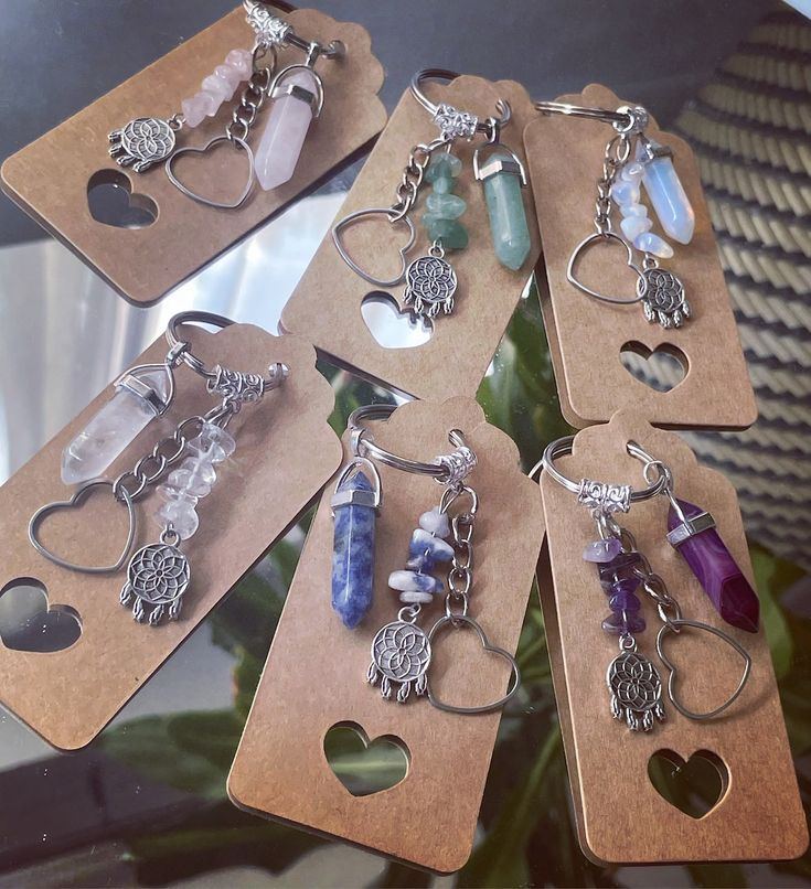 six keychains with various charms on them sitting on top of a wooden table