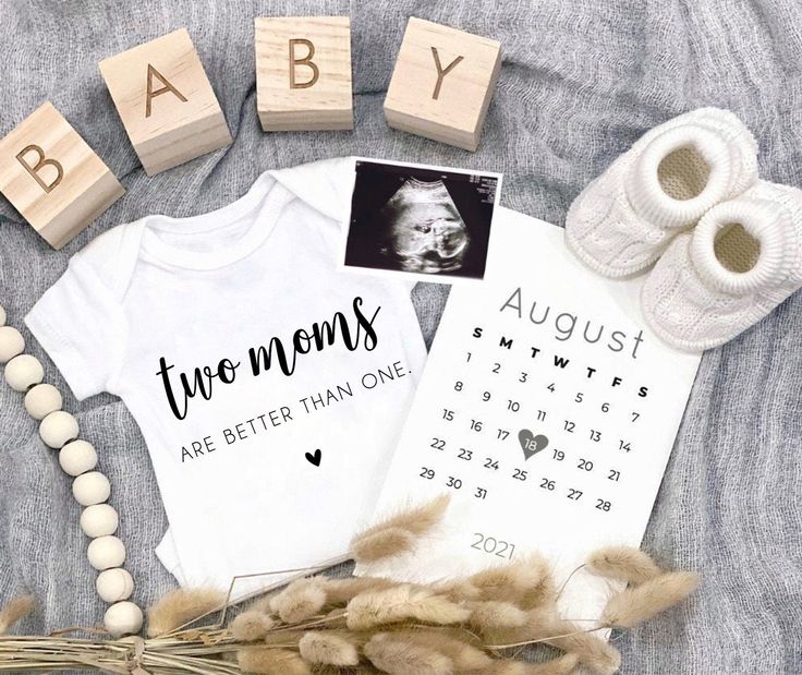 baby announcement with clothes, shoes and birth blocks on the bed next to it's name