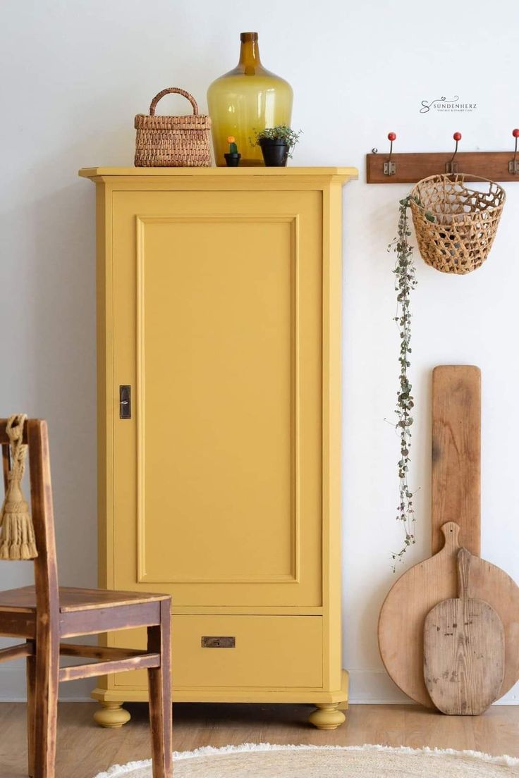 a yellow cabinet sitting next to a wooden chair