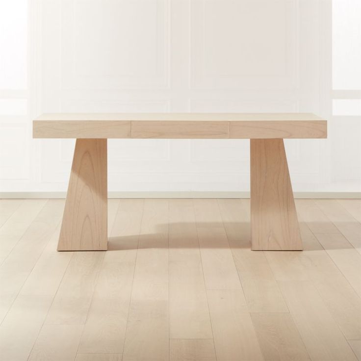 a wooden table sitting on top of a hard wood floor next to a white wall