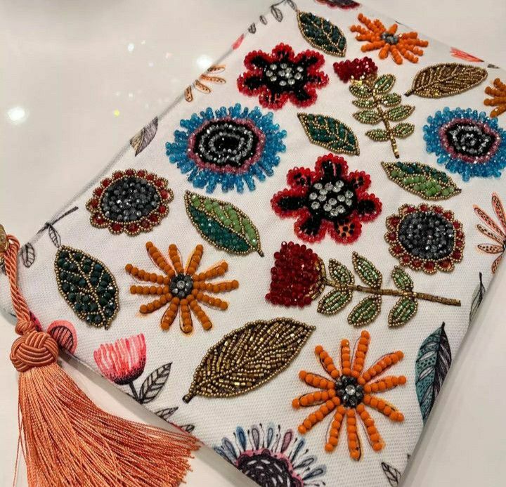 an embroidered book with tassels and flowers on the cover is sitting on a table