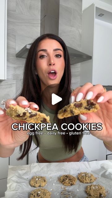 a woman is holding up some cookies in front of her face and making a funny face