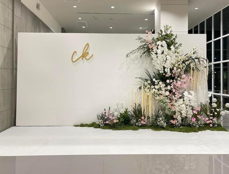 flowers and greenery on display in front of a large sign that reads c k