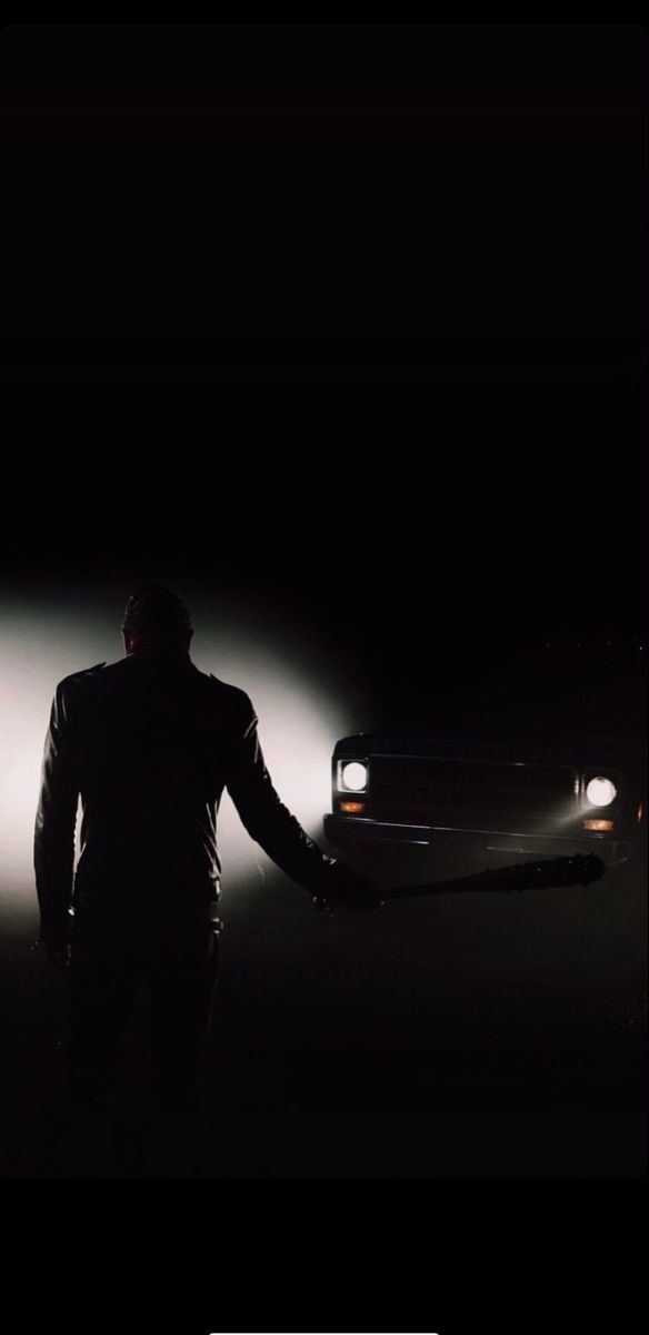 a man standing in front of a car at night with his hands out to the side