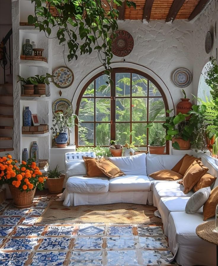 a living room filled with lots of furniture and plants on the wall next to large windows