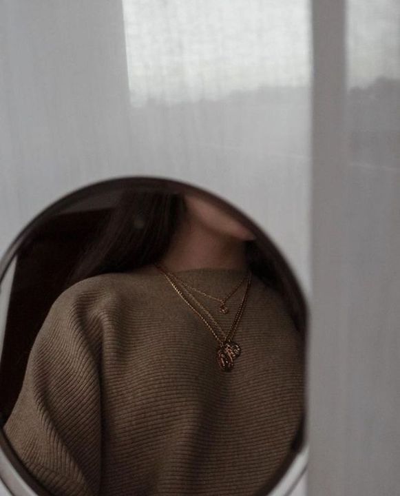 a woman's reflection in a mirror with a necklace on her neck is seen