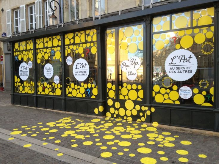 a storefront with yellow circles painted on the windows and in front of it is a sidewalk