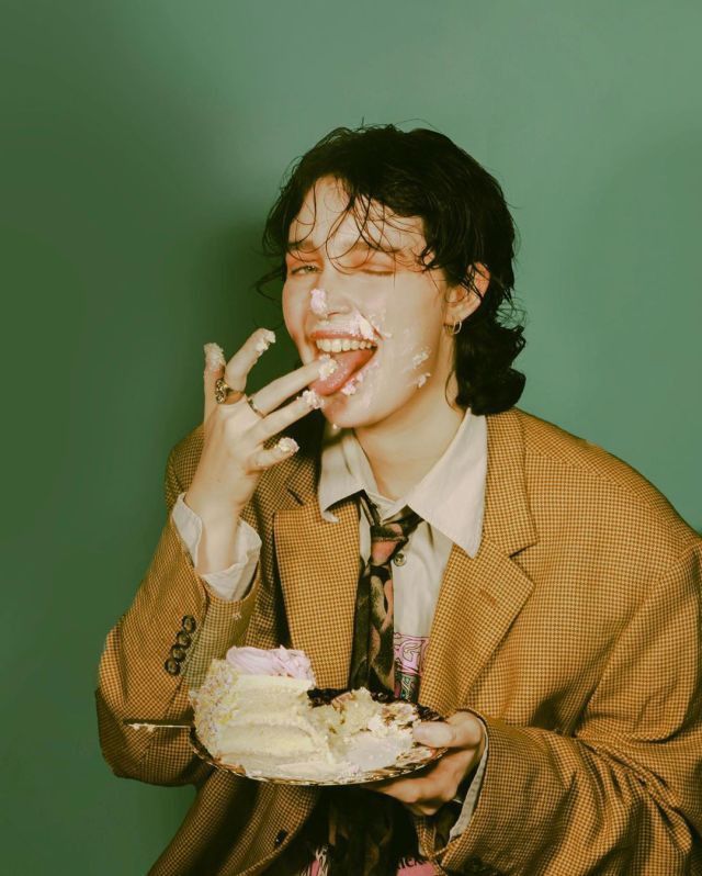 a man in a suit and tie eating cake with frosting on his face while holding a piece of cake