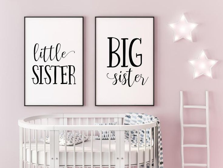 two black and white prints on the wall above a crib in a pink nursery