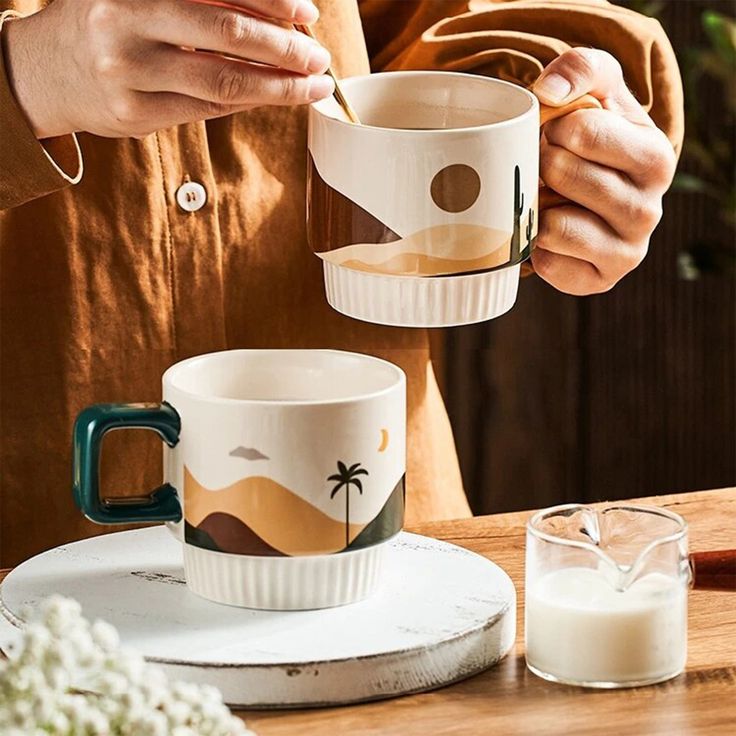 two people holding coffee cups over a wooden table