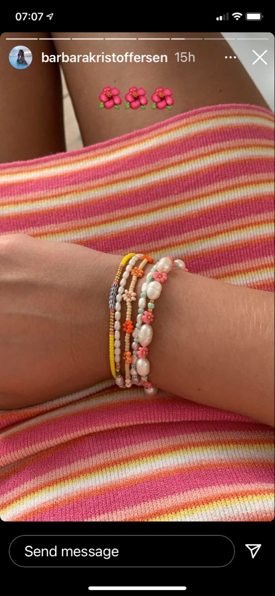 a woman's arm with bracelets and beads on top of her leg, next to a cell phone