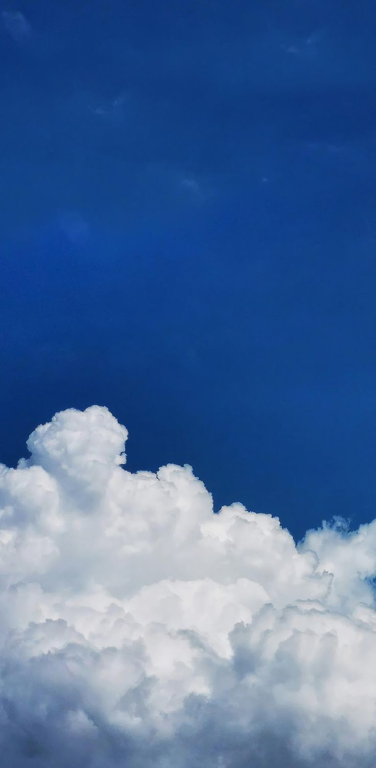 an airplane is flying high in the sky with clouds around it and blue skies above