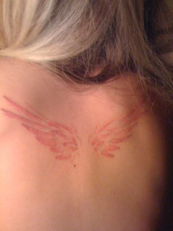 the back of a woman's head with angel wings painted on her upper side