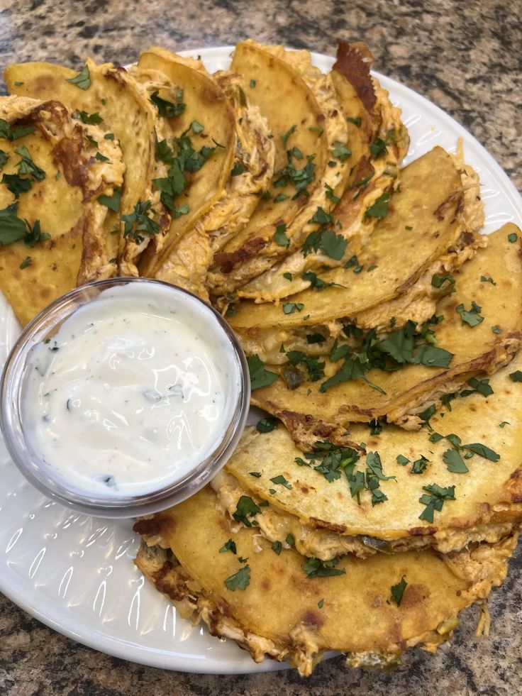 a white plate topped with potato wedges next to a bowl of ranch dressing