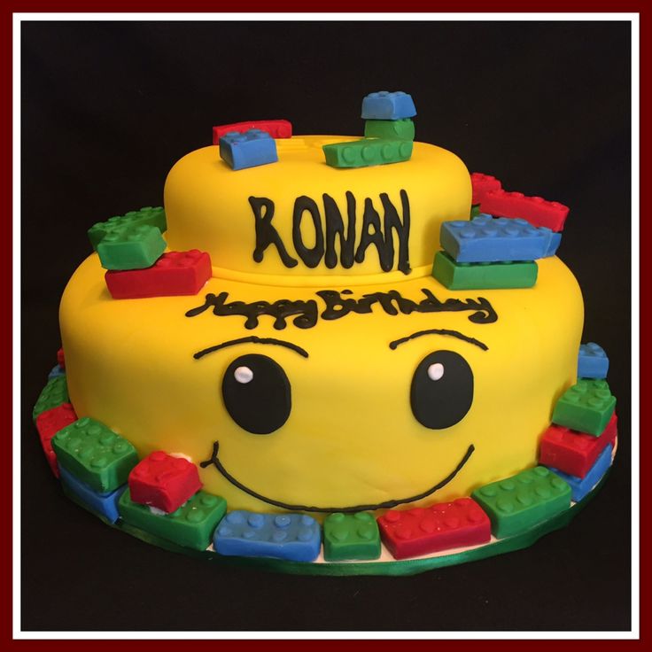 a yellow cake with legos on it and the words rowan spelled in black letters