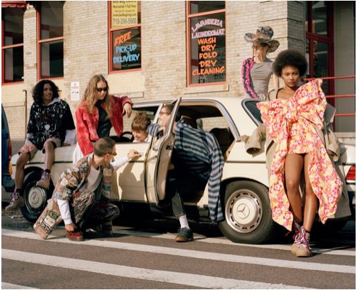 a group of people sitting on the back of a car in front of a building