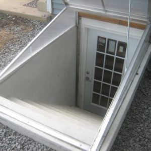 an open door on the side of a house with gravel around it and a metal roof