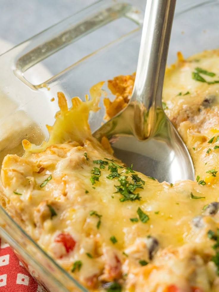 a casserole dish with cheese and vegetables being lifted from the casserole