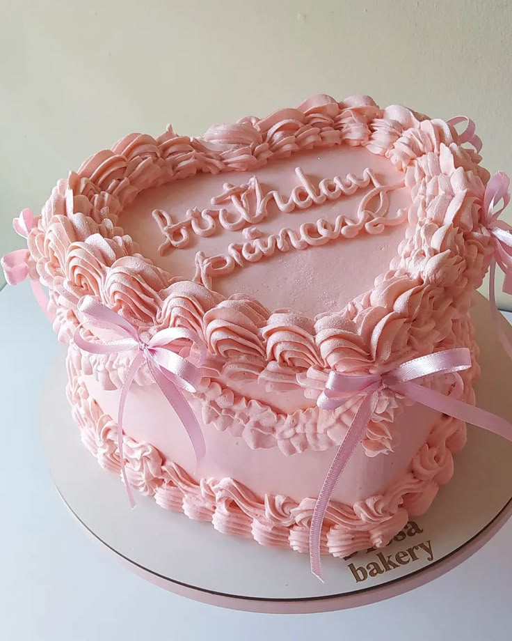 a heart shaped cake with pink frosting and ribbon around the edges that says happy birthday