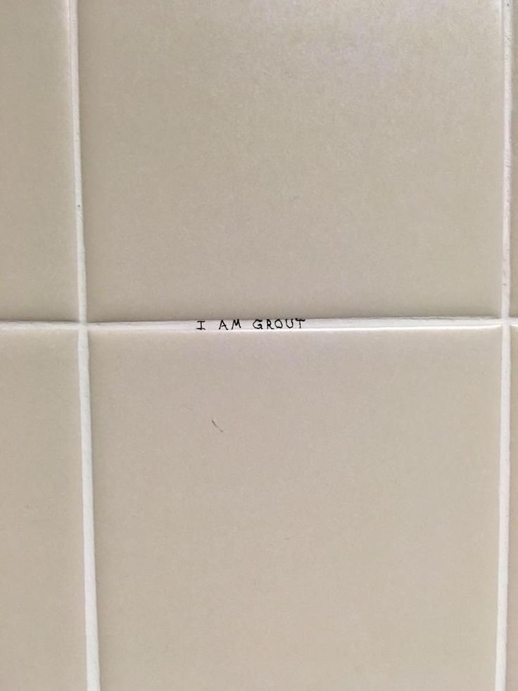 a white tile wall with the word i am sorry written on it in cursive writing