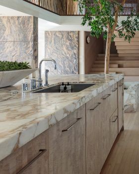 a large kitchen with marble counter tops and wooden stairs leading up to the second floor