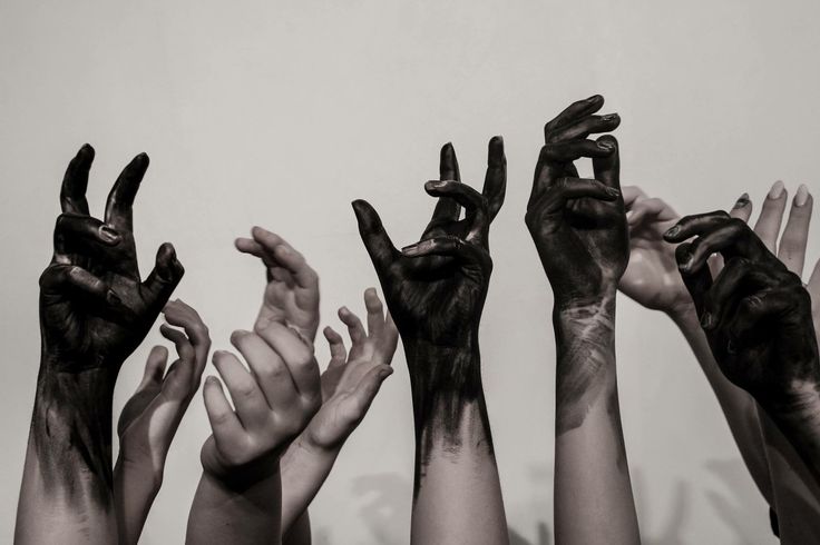 many hands with black paint on them reaching up