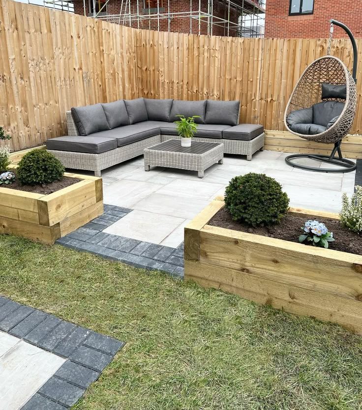 an outdoor patio with wooden planters and couches in the middle, surrounded by grass