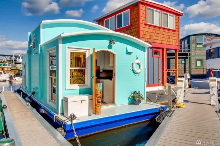 a houseboat docked at a dock with other boats in the water and houses on either side