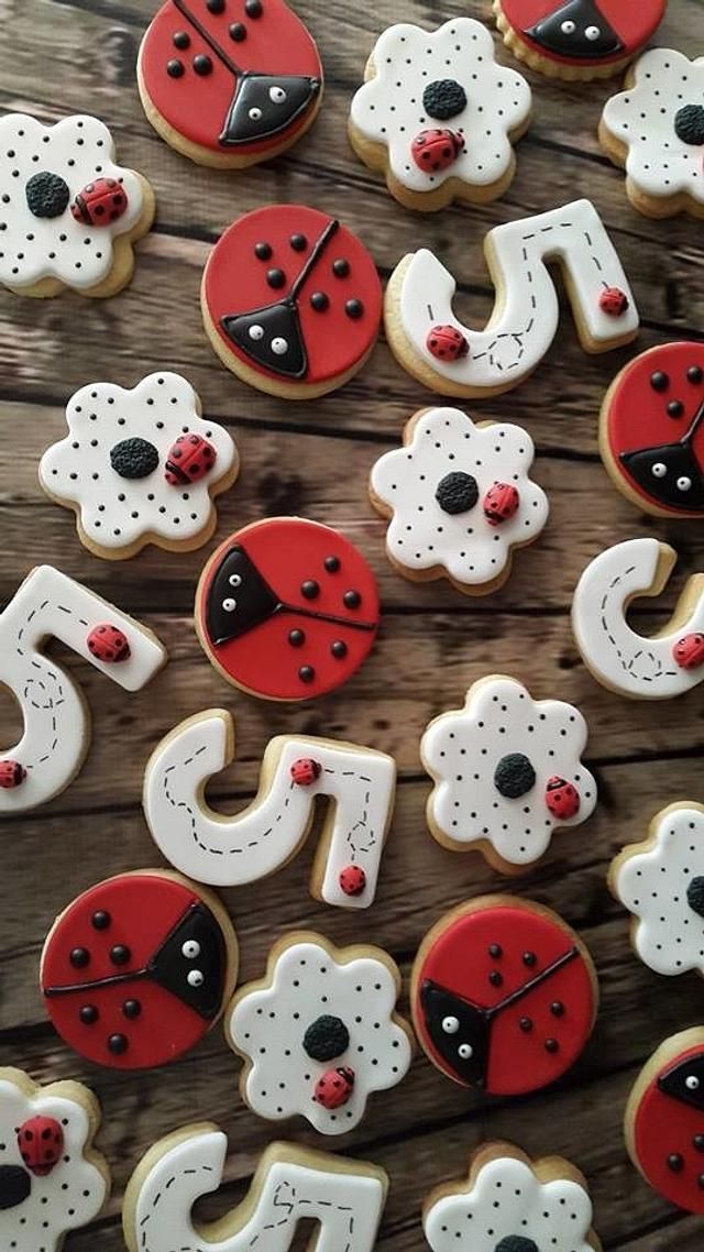 decorated cookies with ladybug and dog faces on wooden table next to each other