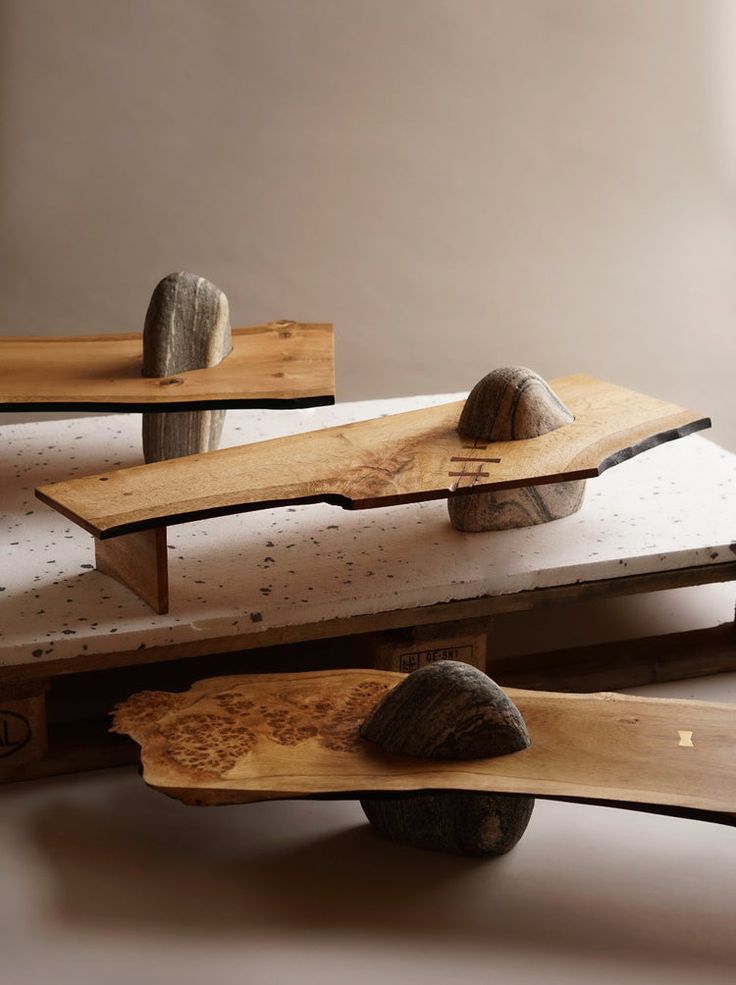 three wooden skateboards stacked on top of each other with rocks in the middle and wood planks attached to them