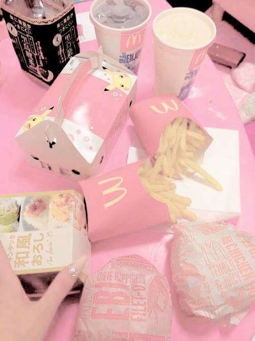 a pink table topped with lots of fast food and drink bottles on top of it