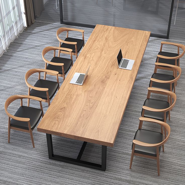 a conference table with chairs around it and a laptop on the desk in front of it