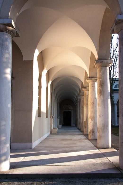 an arched walkway between two buildings with columns