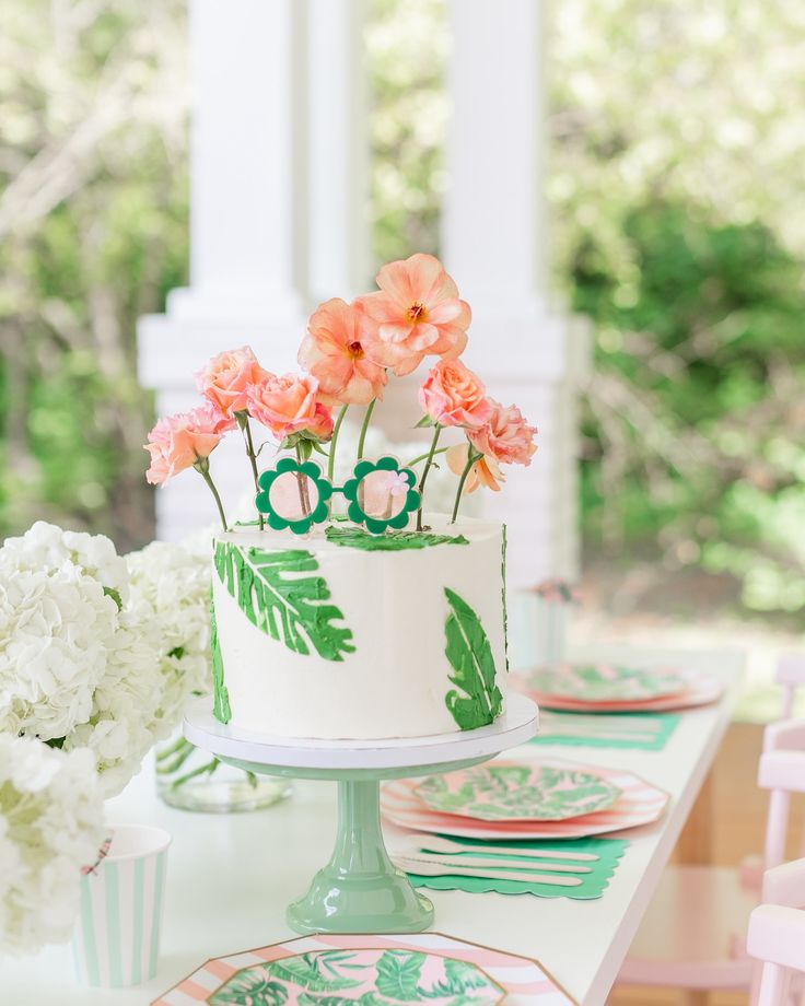 a decorated cake on a table with plates and flowers