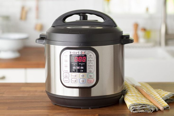 an electric pressure cooker sitting on top of a wooden table next to a yellow and white towel