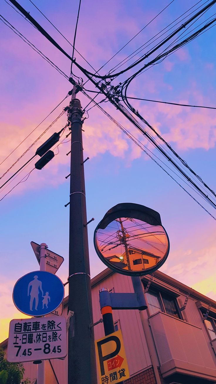 an apple sign and street signs on a pole in front of a building at sunset