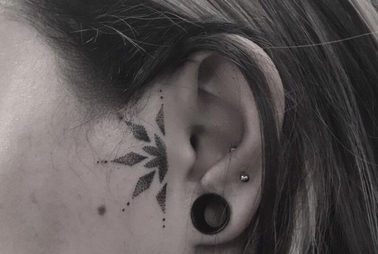 a woman's ear has a small flower tattoo on it