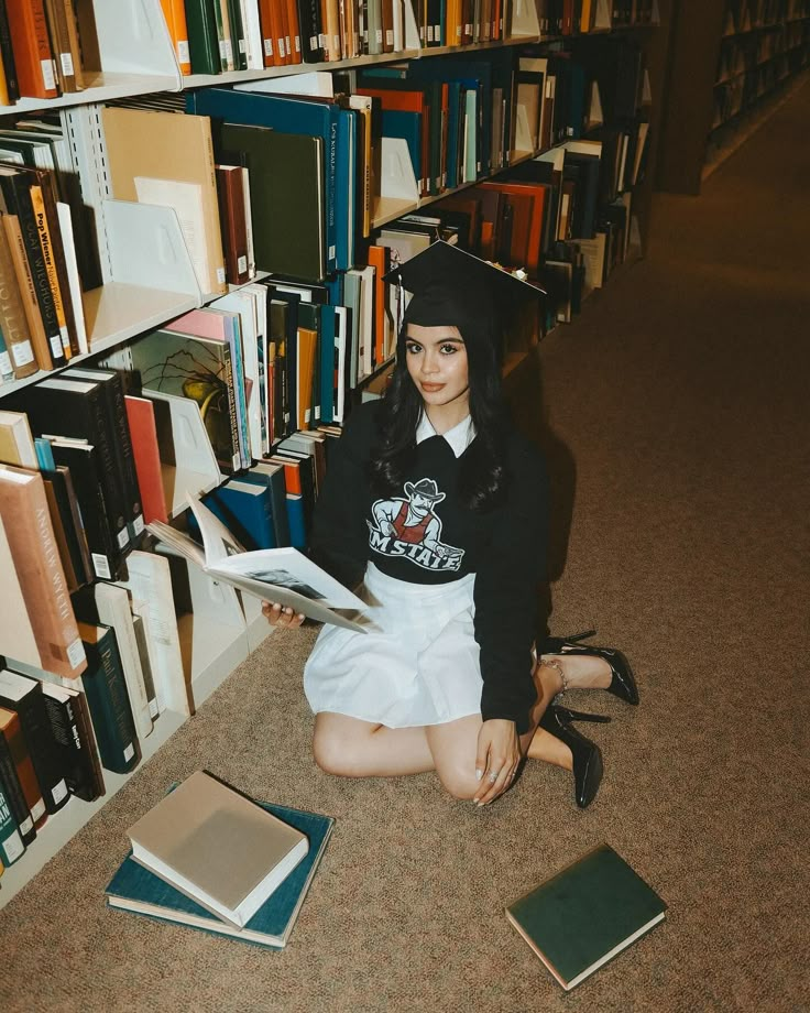 a young woman sitting on the floor in front of bookshelves and holding a book