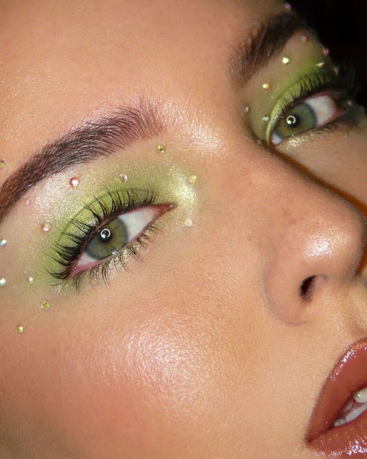 a woman with green and gold makeup looks at the camera while she has her eyes closed