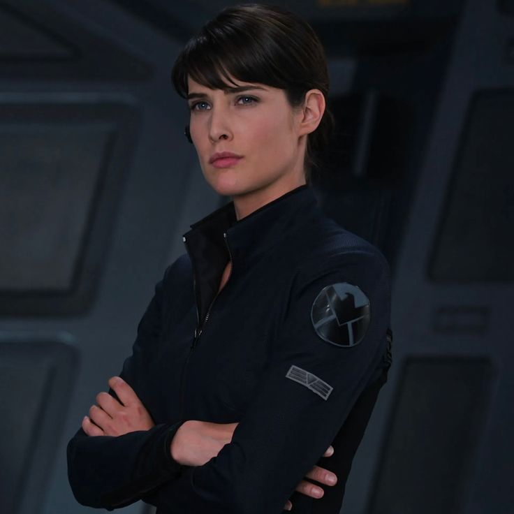 a woman standing with her arms crossed and looking at the camera while wearing a star trek uniform