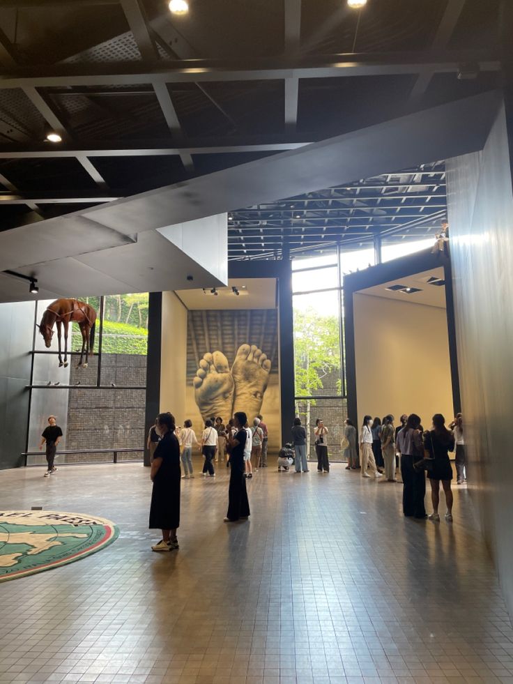 people are standing in an open space with art on the walls